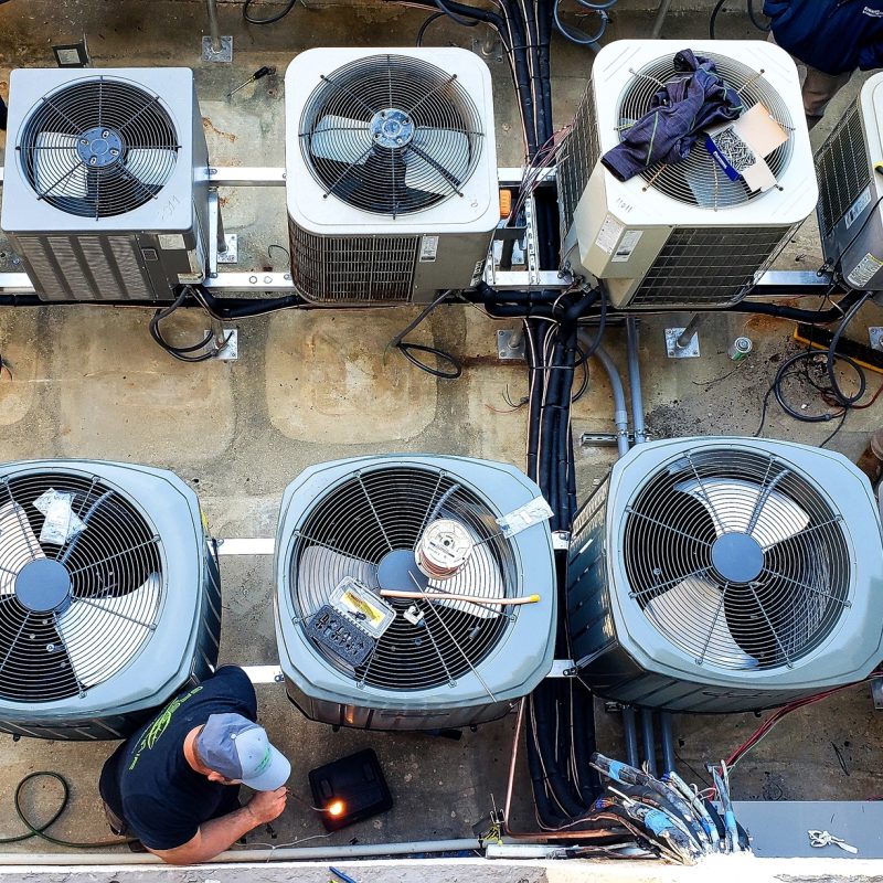 Overhead of utility workers maintaining outside air conditioning HVAC units at a beach condo.